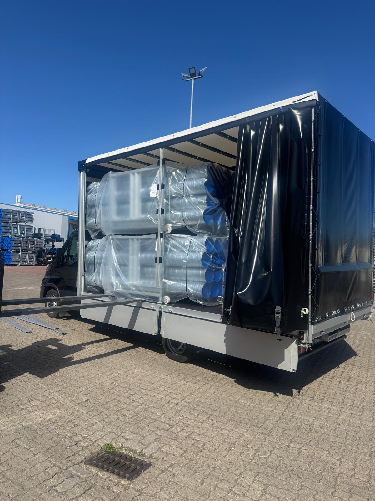 Naczepa załadowana rurami i pojemnikami – transport przemysłowy Niemcy